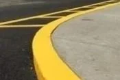 Close-up of a road curb with yellow paint marking