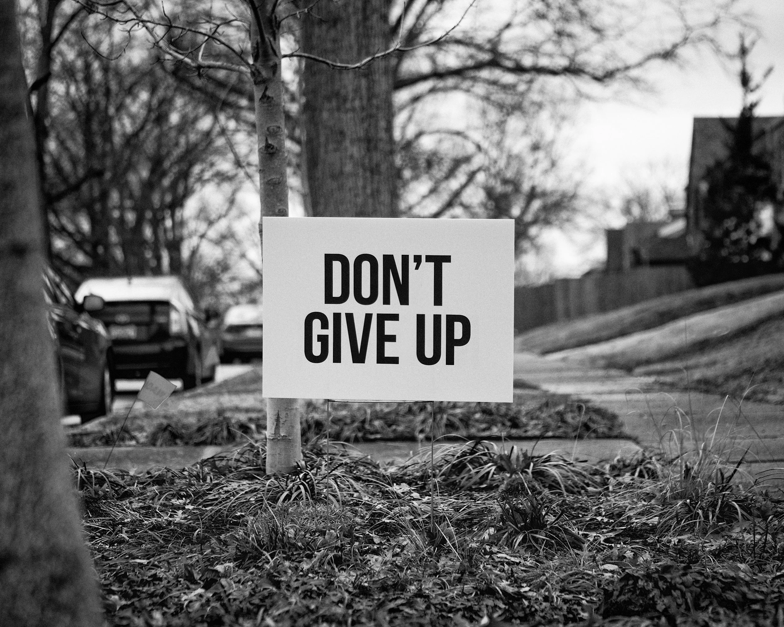 Black-and-white photo of a "Don't Give Up" sign representing hope, resilience, and healing in therapy for trauma, anxiety, and OCD.