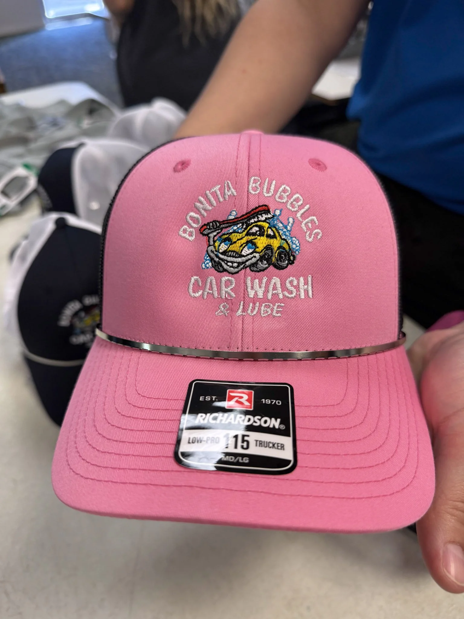 Pink trucker cap embroidered with a yellow car, water splash, and the text "Bonita Bubbles Car Wash & Lube".
