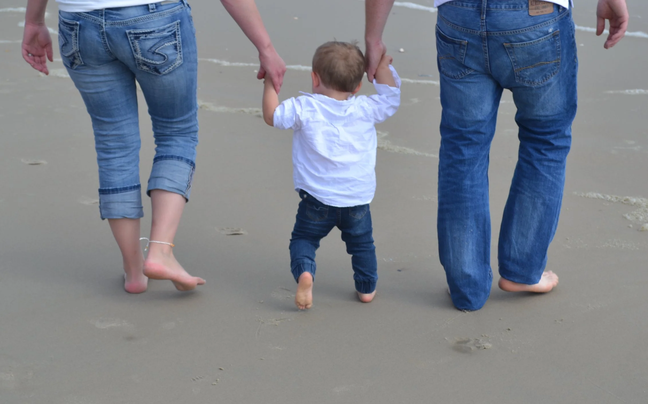 Parents walking on beach with child with immature reflexes receiving reflex integration. - Kalme Key Therapeutics