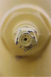 Close-up of a yellow plastic bottle opening, showing the inside threading and cap area.