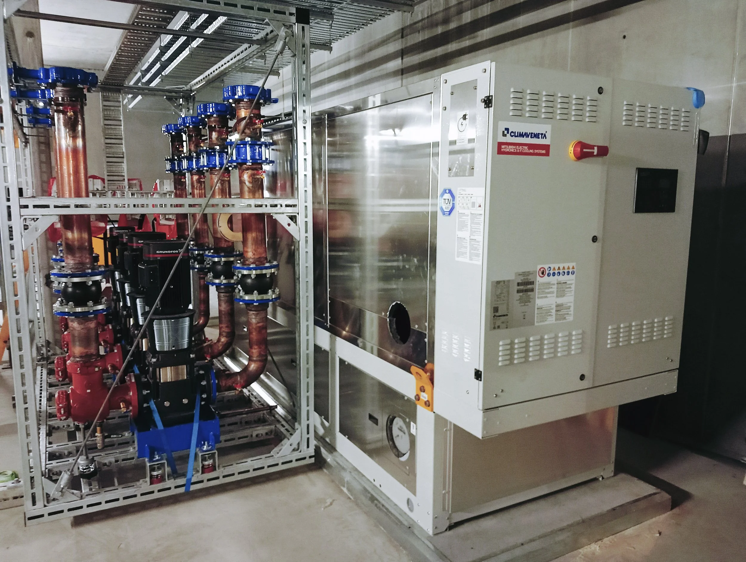 Industrial HVAC chiller system with copper pipes and valves on a metal frame.