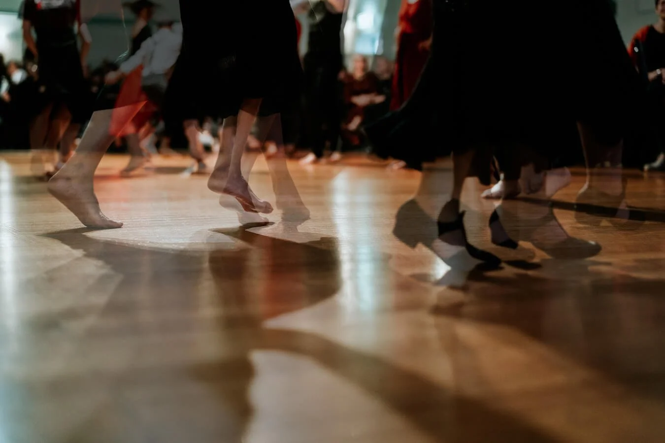 People dancing barefoot on a wooden floor at a dance event or class.