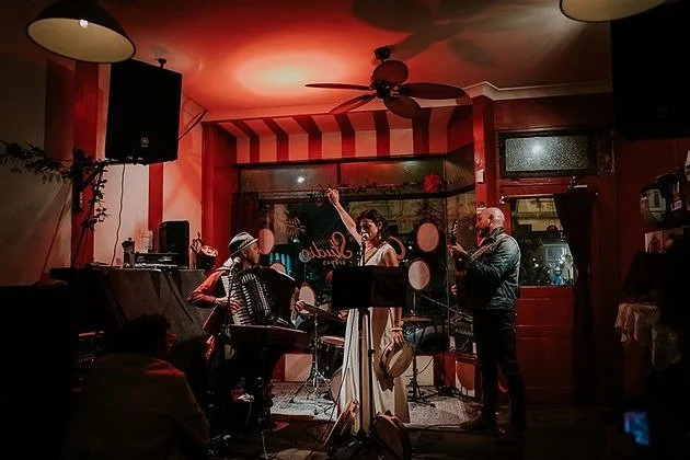 Live jazz band performing in a cozy restaurant with red striped walls, a ceiling fan, and warm lighting.