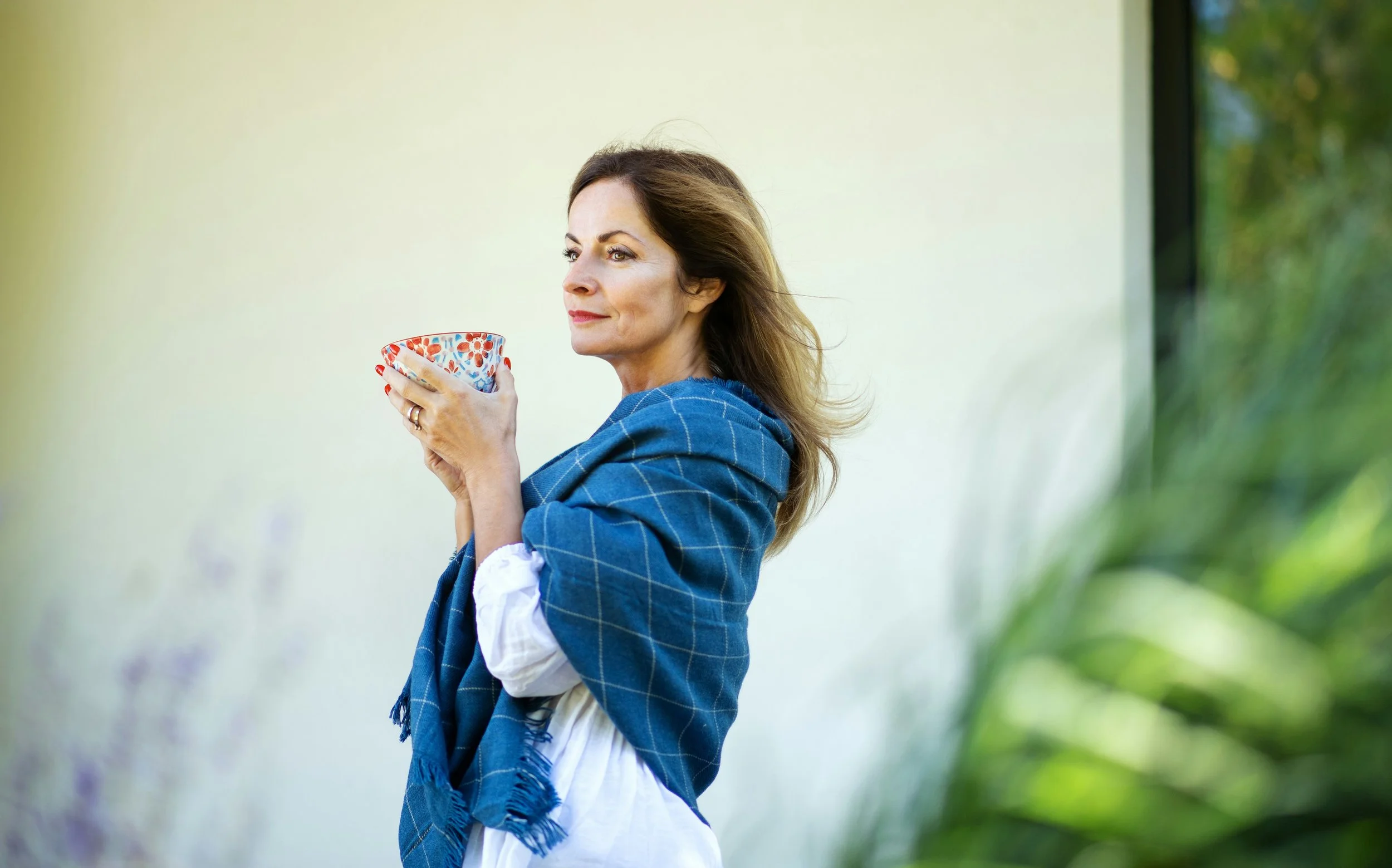 Midlife woman reflecting outdoors holding tea representing menopause metabolism and energy changes