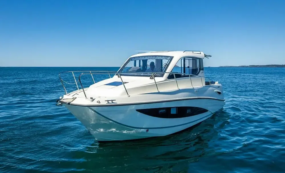 A white motor yacht boat on calm blue ocean water under a clear blue sky.