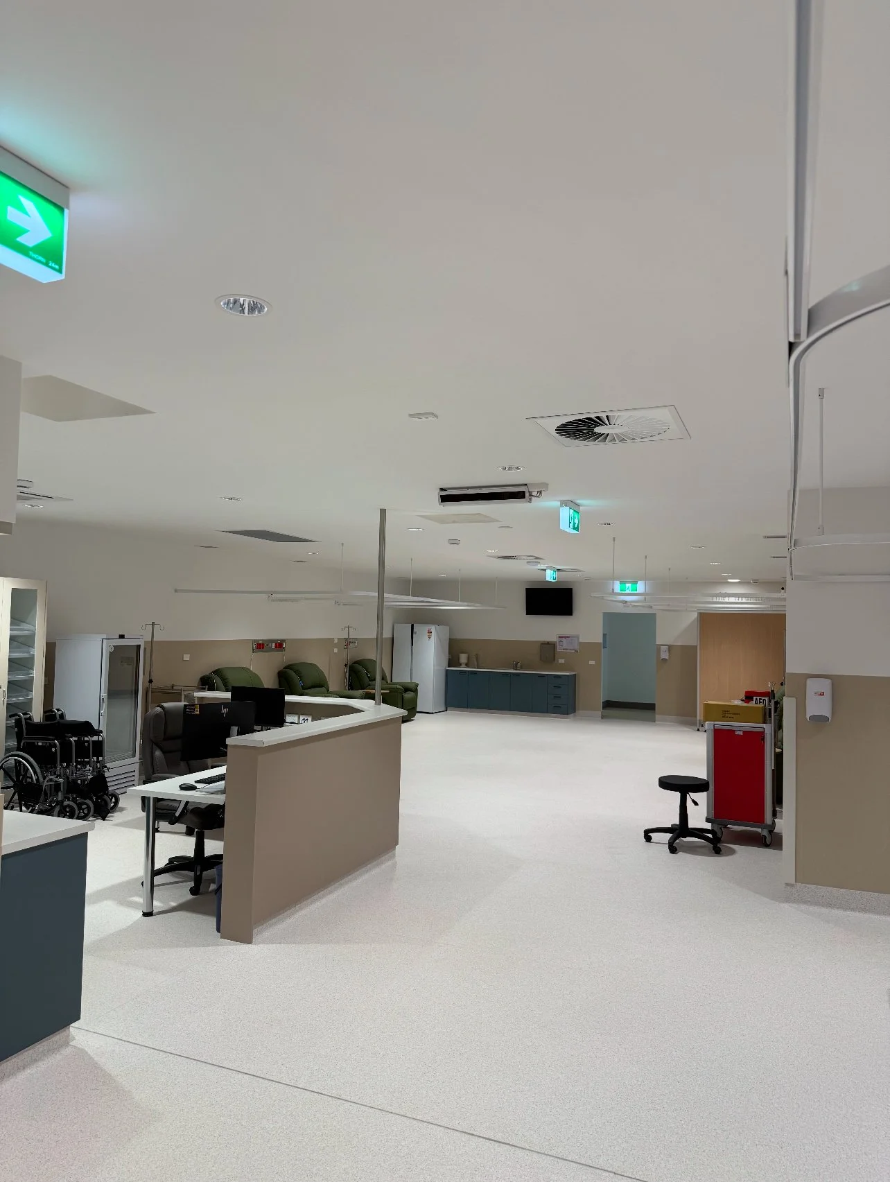 Empty hospital or clinic reception area with chairs, medical equipment, and computer desks.