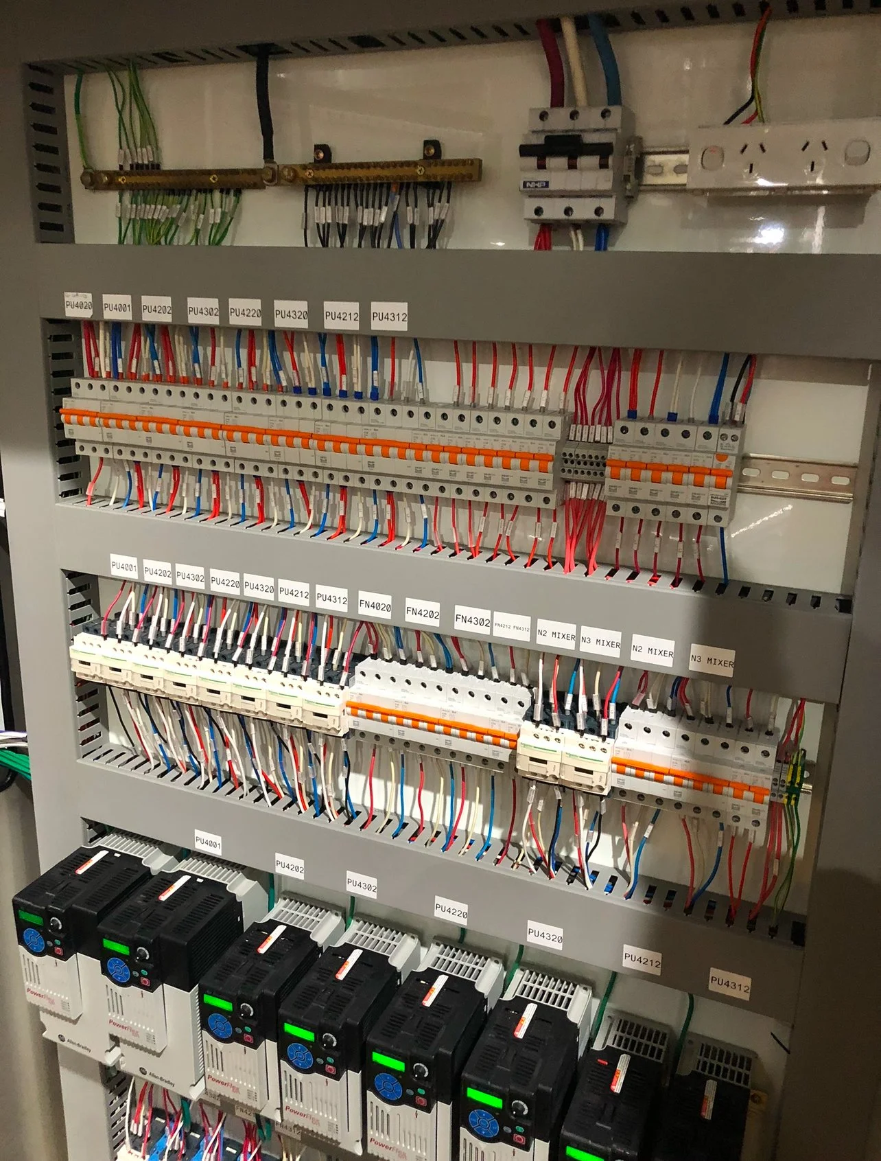 Electrical control panel with wires, circuit breakers, relays, and power supplies.