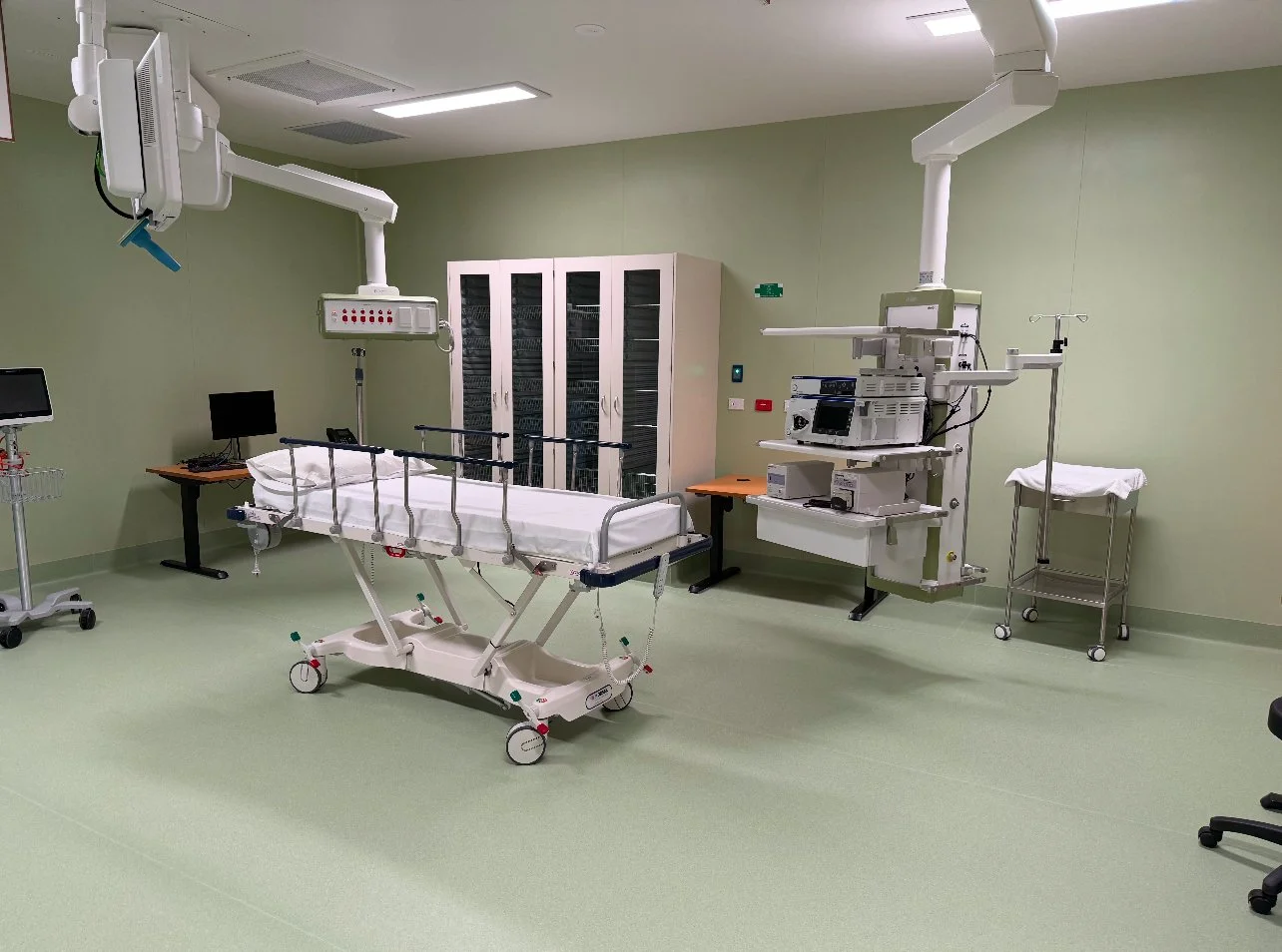Empty hospital operating room with medical equipment, hospital bed, monitors, and mobile instruments.