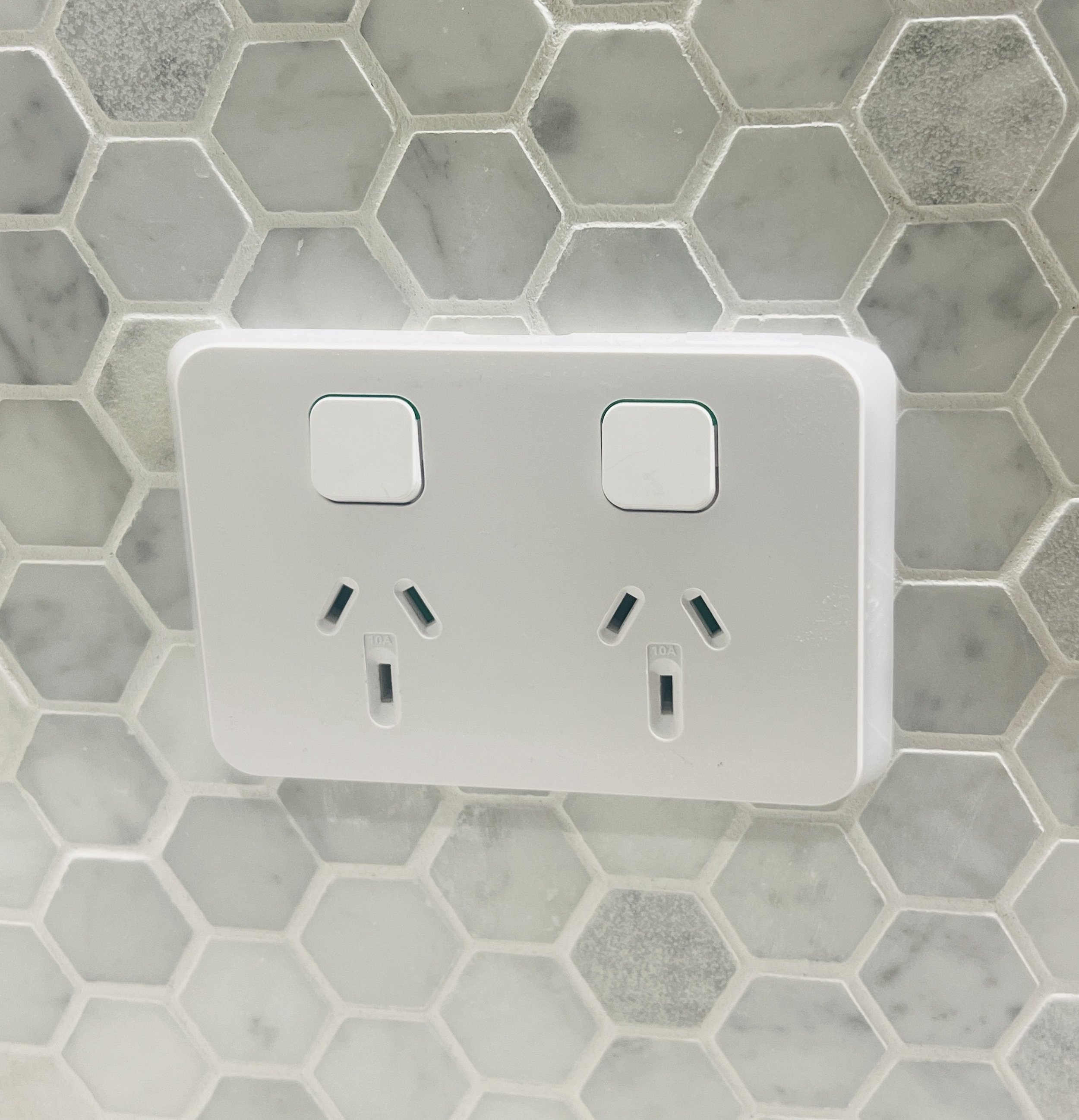 White double power point on a gray hexagonal marble tile wall in a new home. Power point installation in Launceston