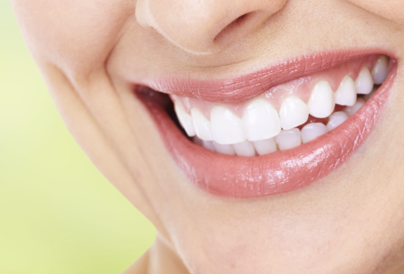 Close-up of a woman's smile showing her white teeth and pink lips.