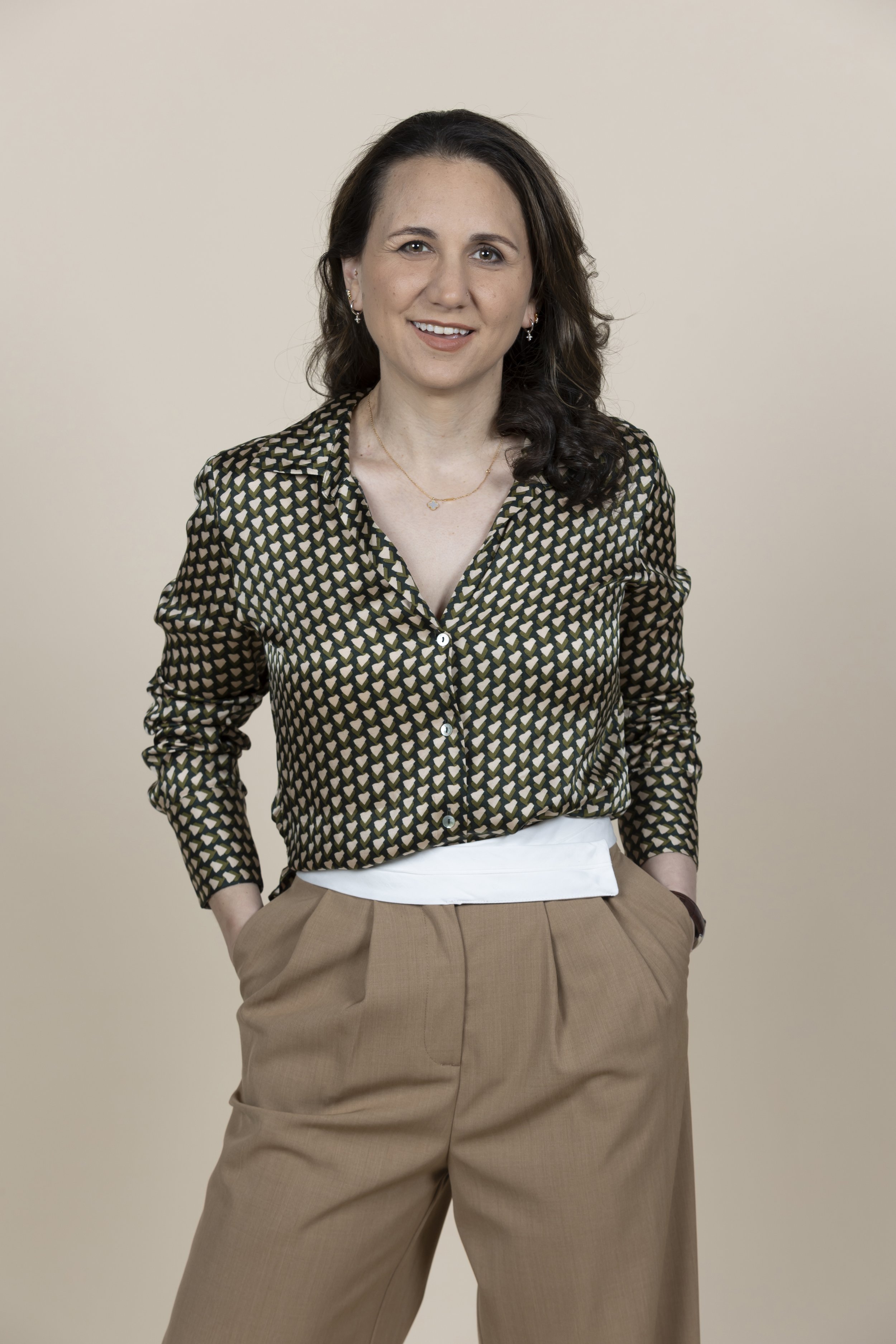 Portrait of psychologist Sara Waitzer in a patterned blouse against a beige background.