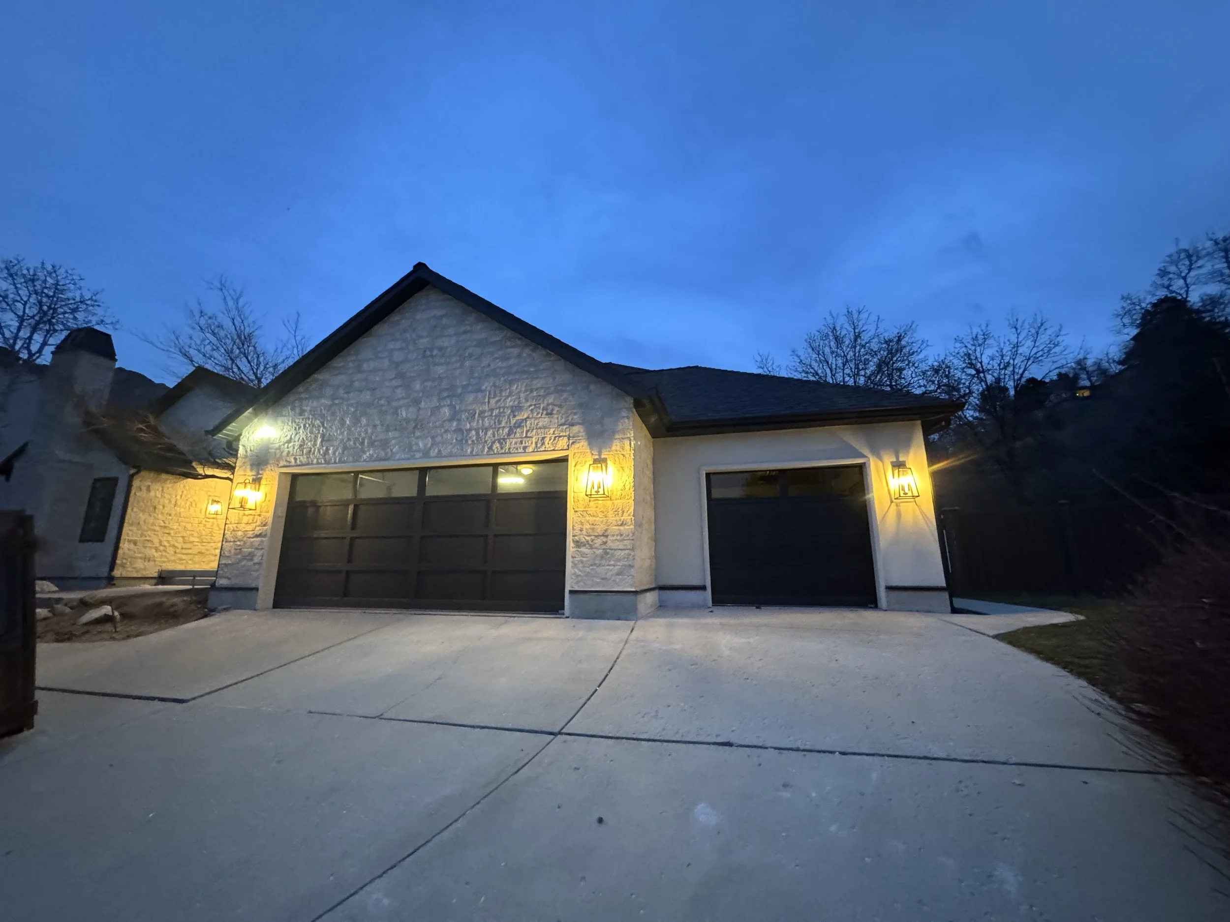 A modern house at dusk with exterior lights on.