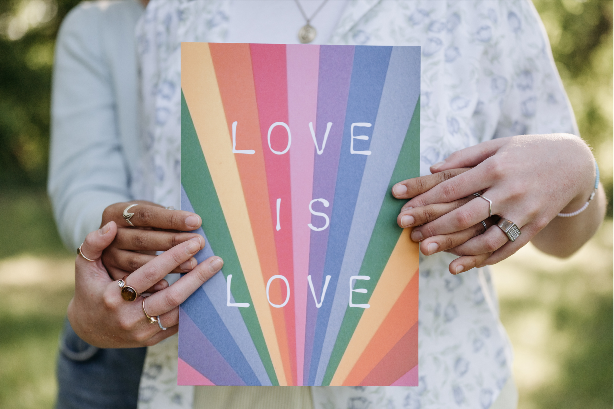 OnlyVibes Open to LGBTQ+ Love: Person holding colorful sign that says 'LOVE IS LOVE' with a rainbow pattern. Display this vibe when you want to meet someone special in LGBTQ+ community.