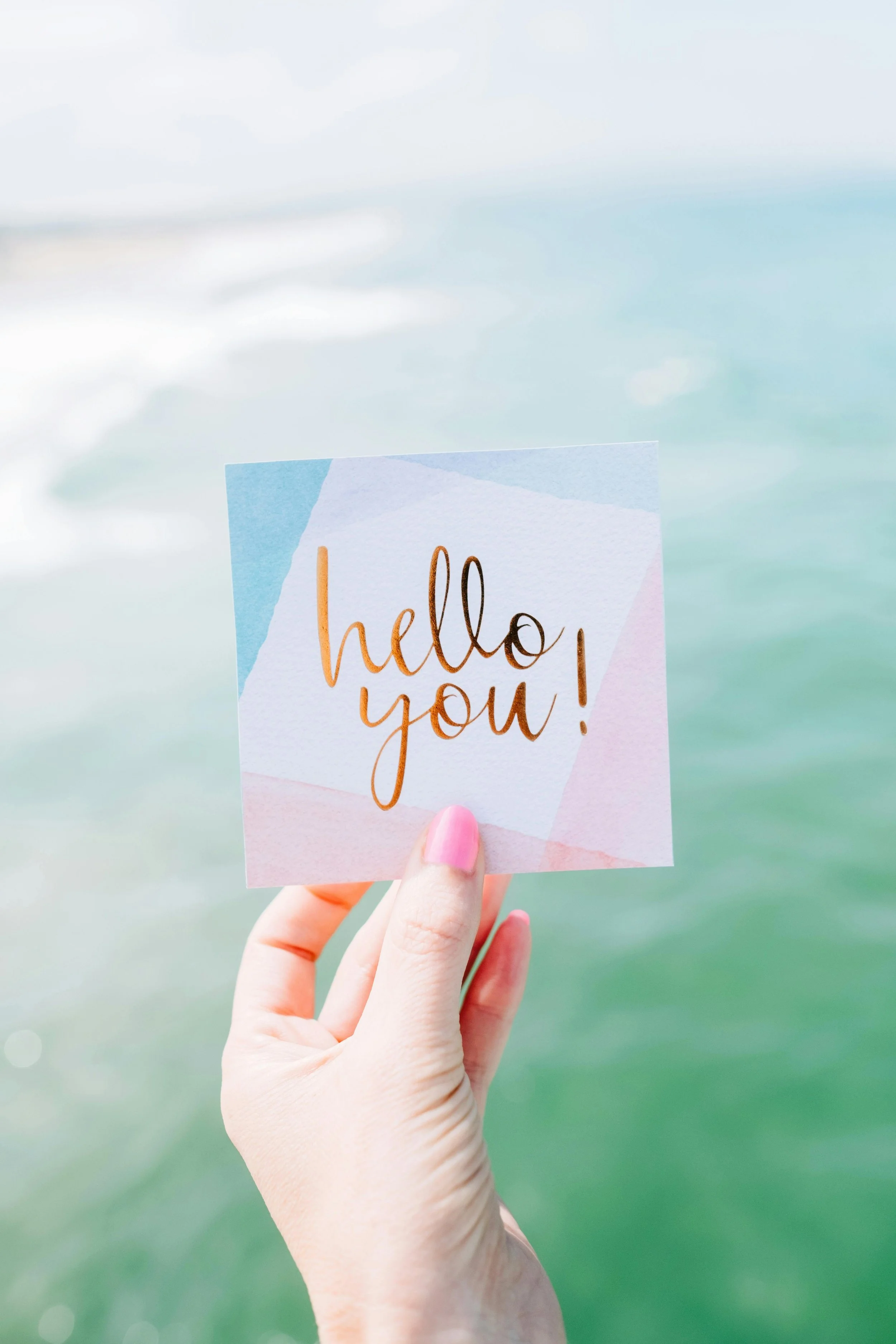 Hand holding a note that says “hello you!” representing compassionate support and encouragement for adults navigating anxiety and emotional overwhelm.