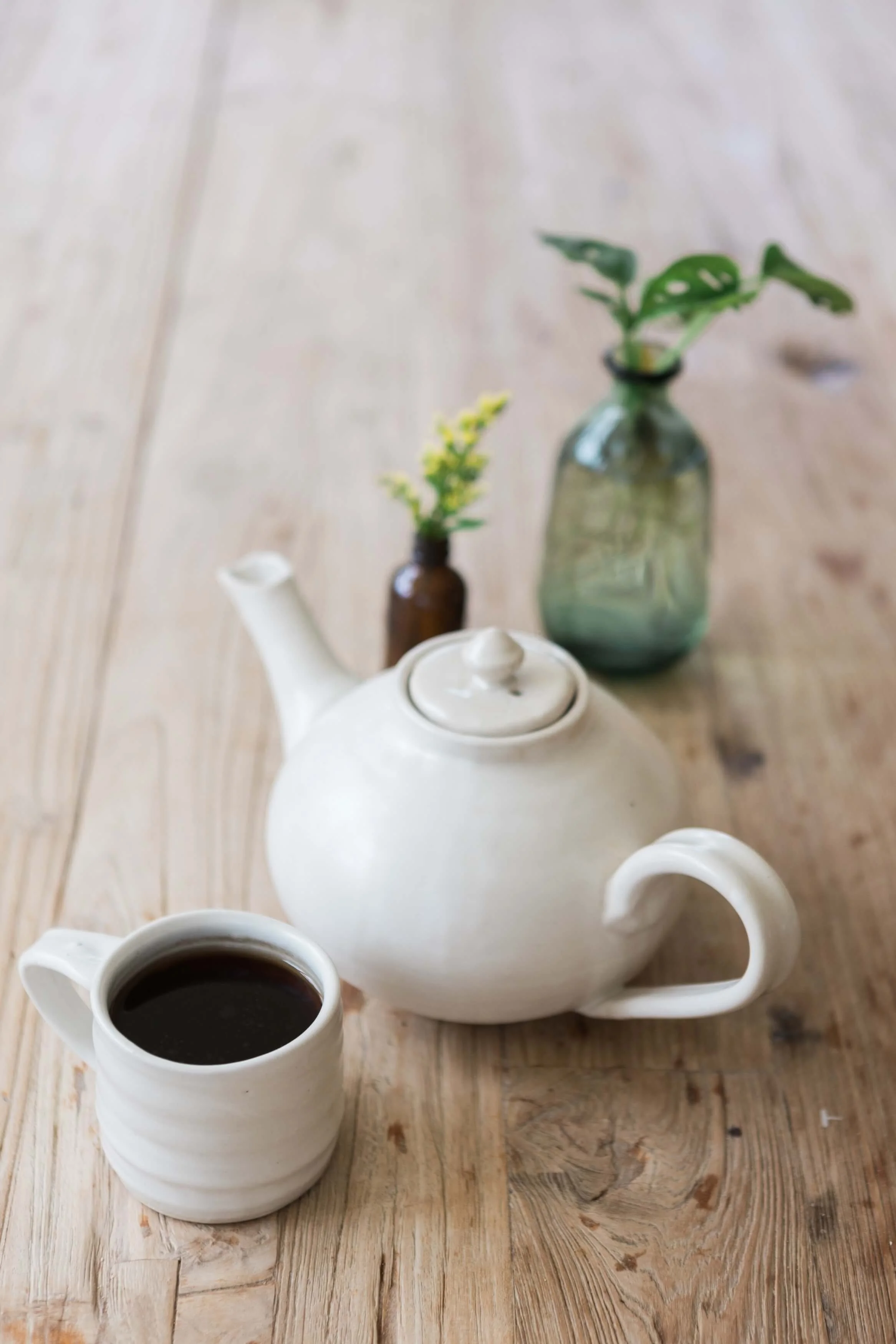 Teapot, coffee cup, and small vase on a wooden table