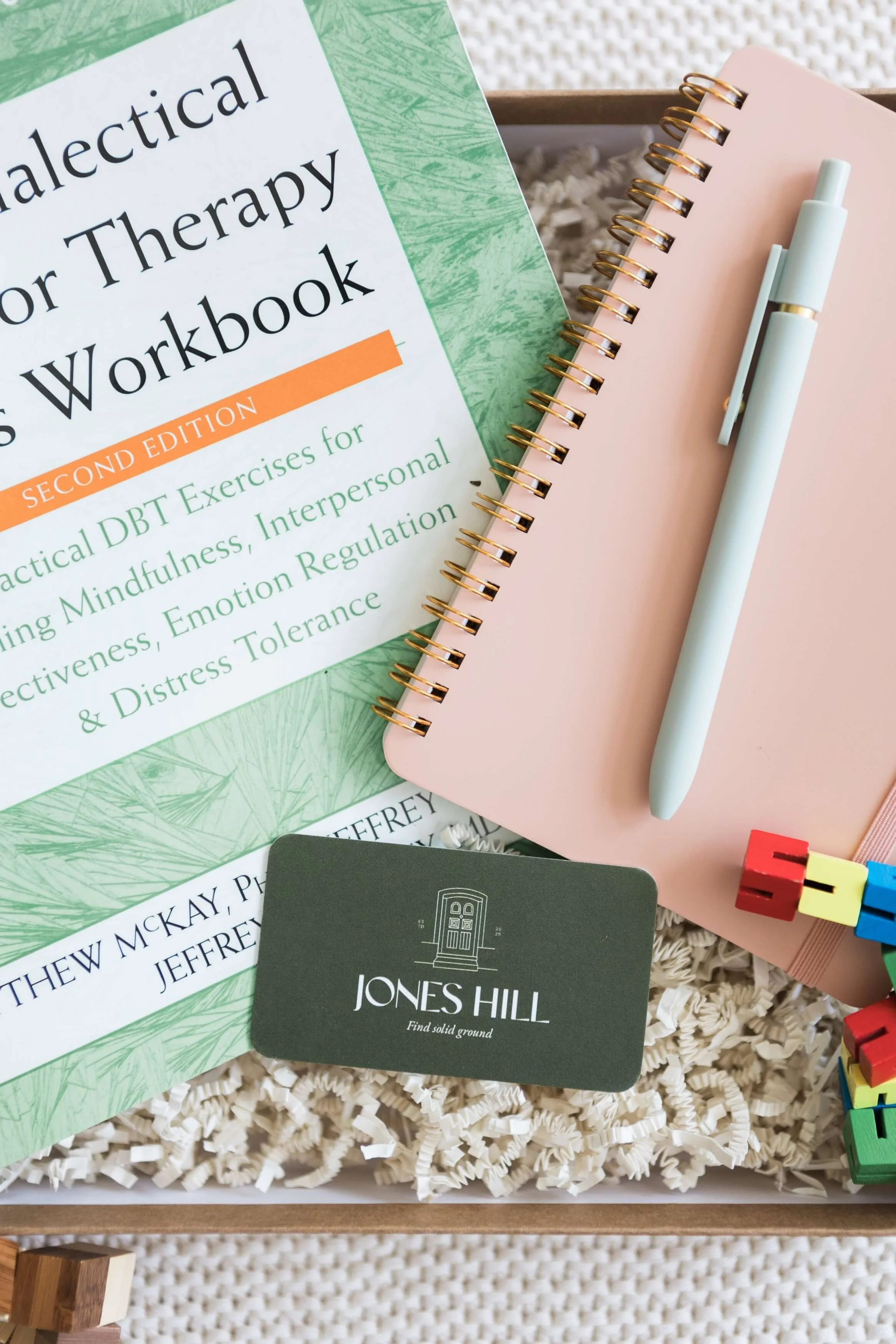 DBT therapy workbook, notebook, and pen on a desk