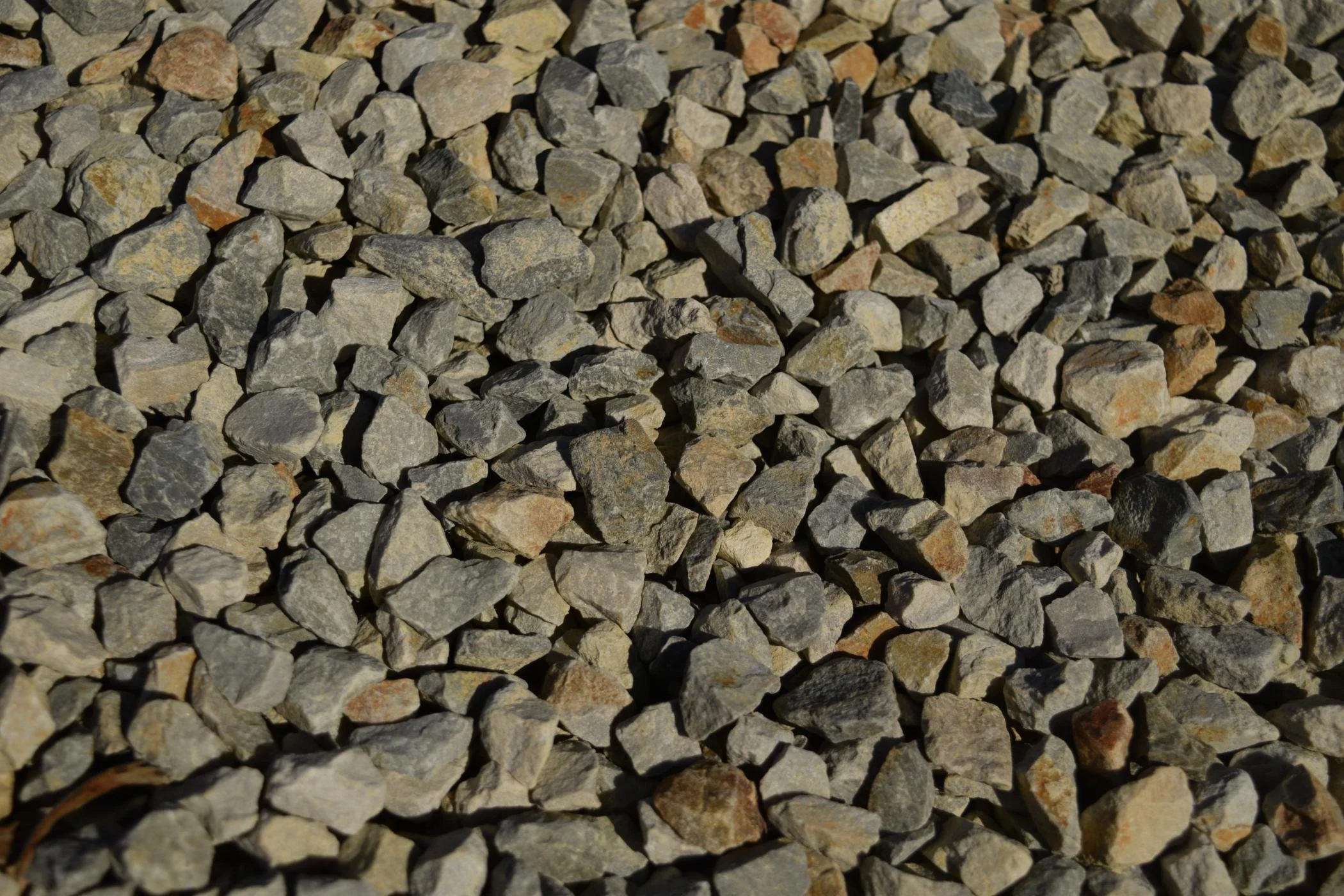 Close-up of small gray and beige gravel stones spread on the ground.