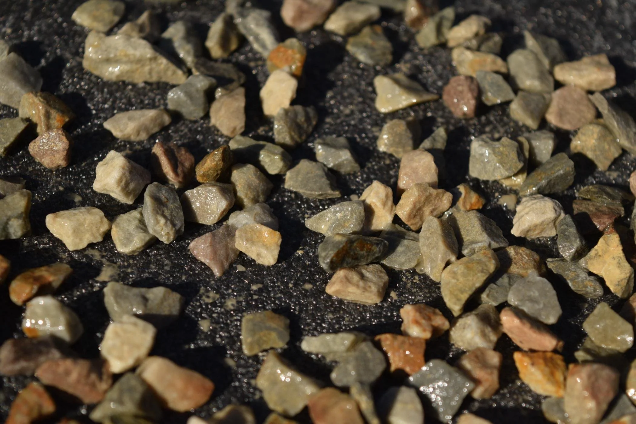 Close-up of a gravel surface with various small, pointed rocks of different colors and textures.