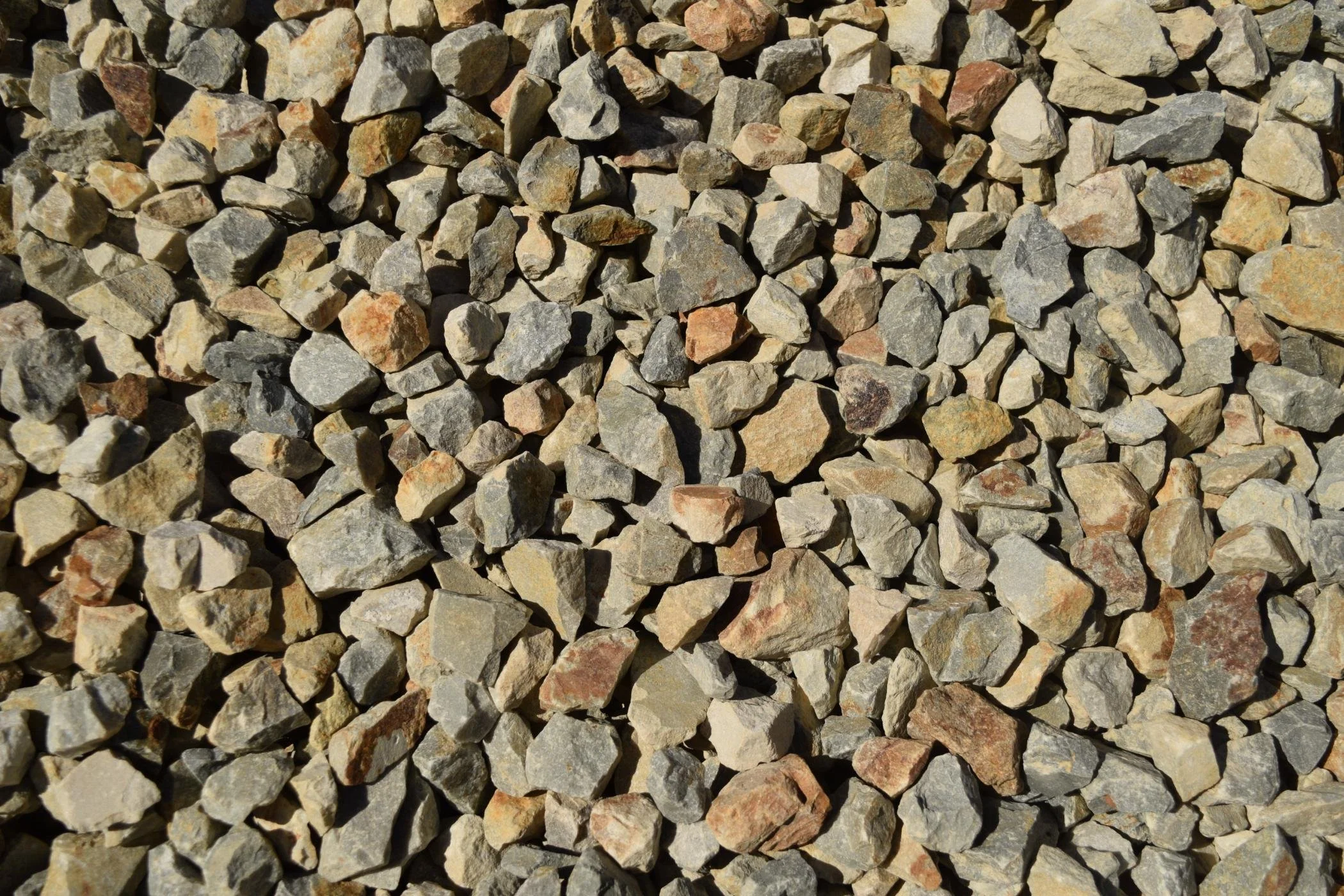 Close-up of small, irregularly shaped rocks with shades of gray, tan, and reddish-brown.