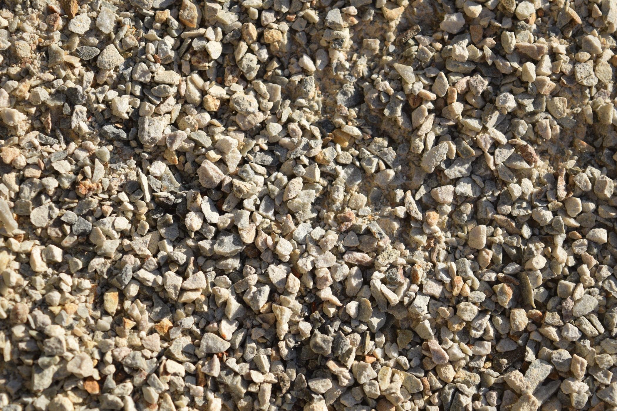 Close-up of small, irregularly shaped gravel stones with various shades of beige, gray, and light brown.