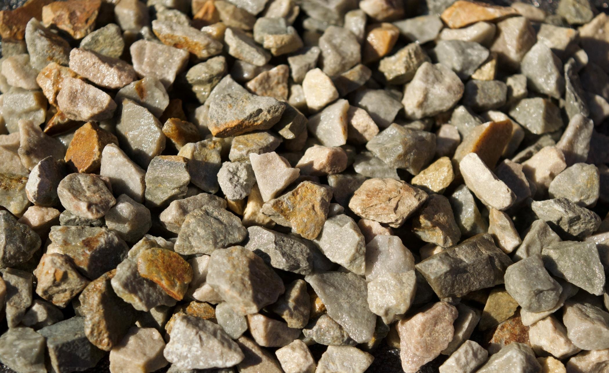 Close-up of small, irregularly shaped rocks and gravel of various shades of gray, tan, and light brown.