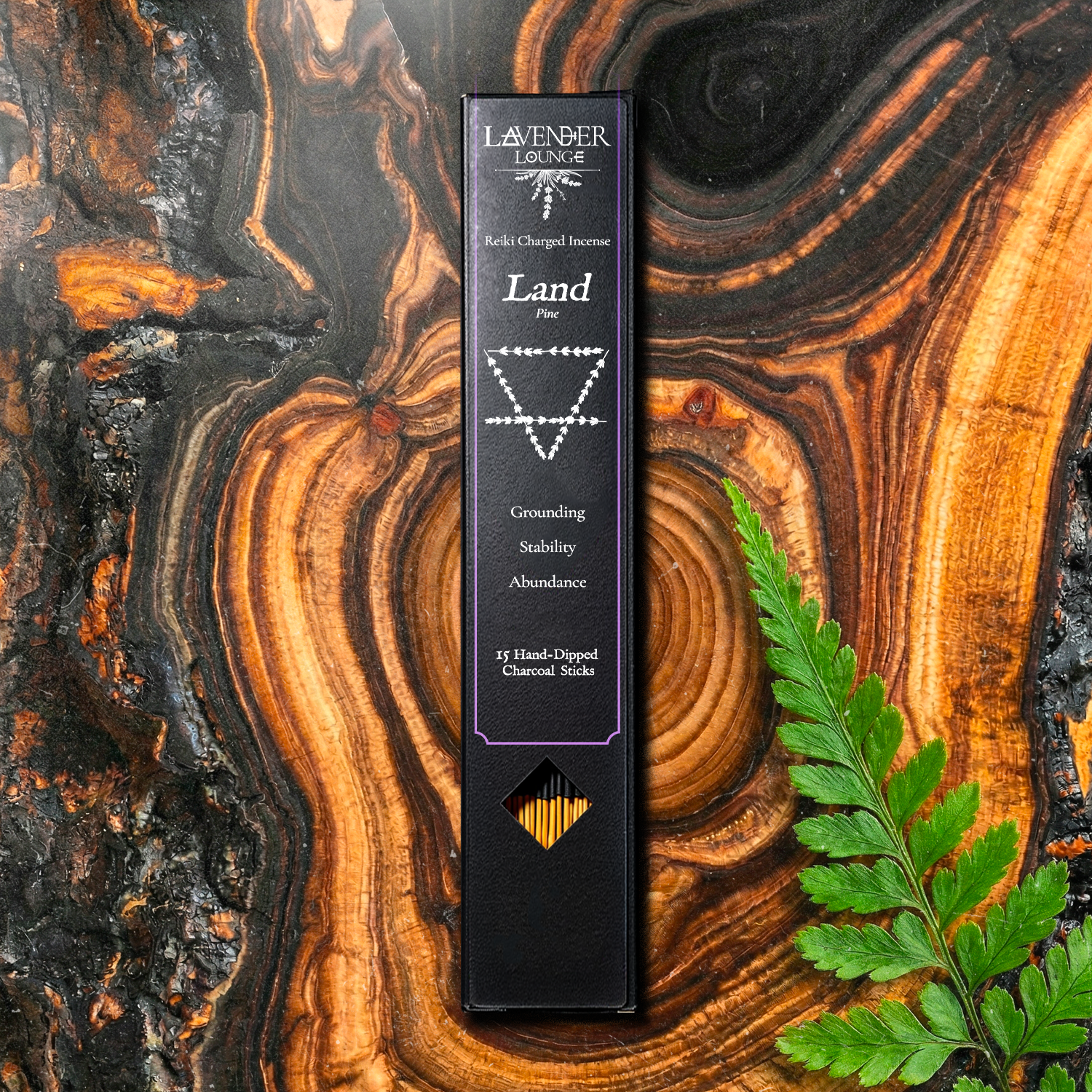 Sanctuary Incense (Land — Pine) box flat lay on bright orange-and-yellow wood cross-section slab with fern leaf