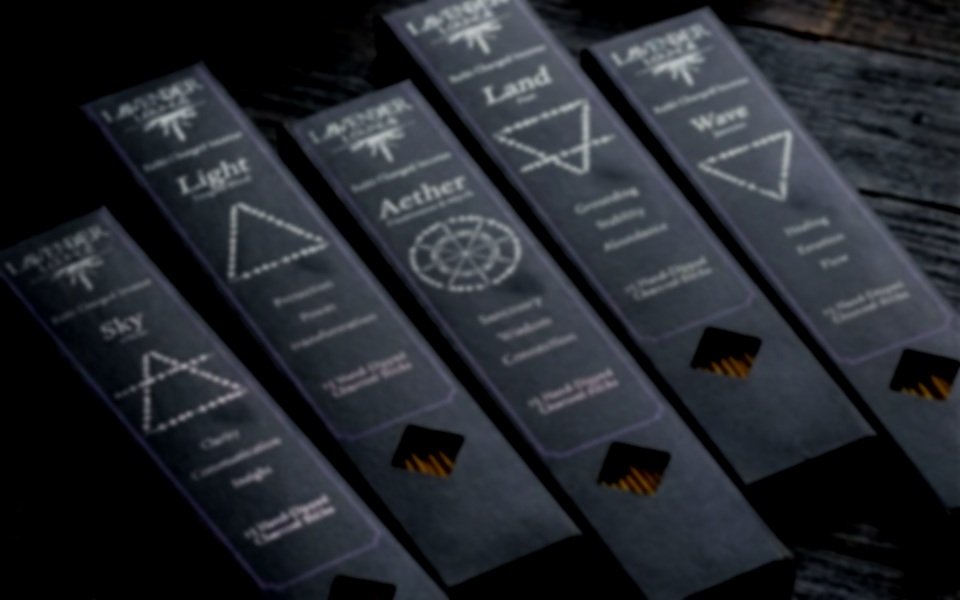 A box of lavender incense sticks surrounded by small, colorful stones or crystals on black fabric with white paisley patterns, and a metallic pentagram-shaped object.