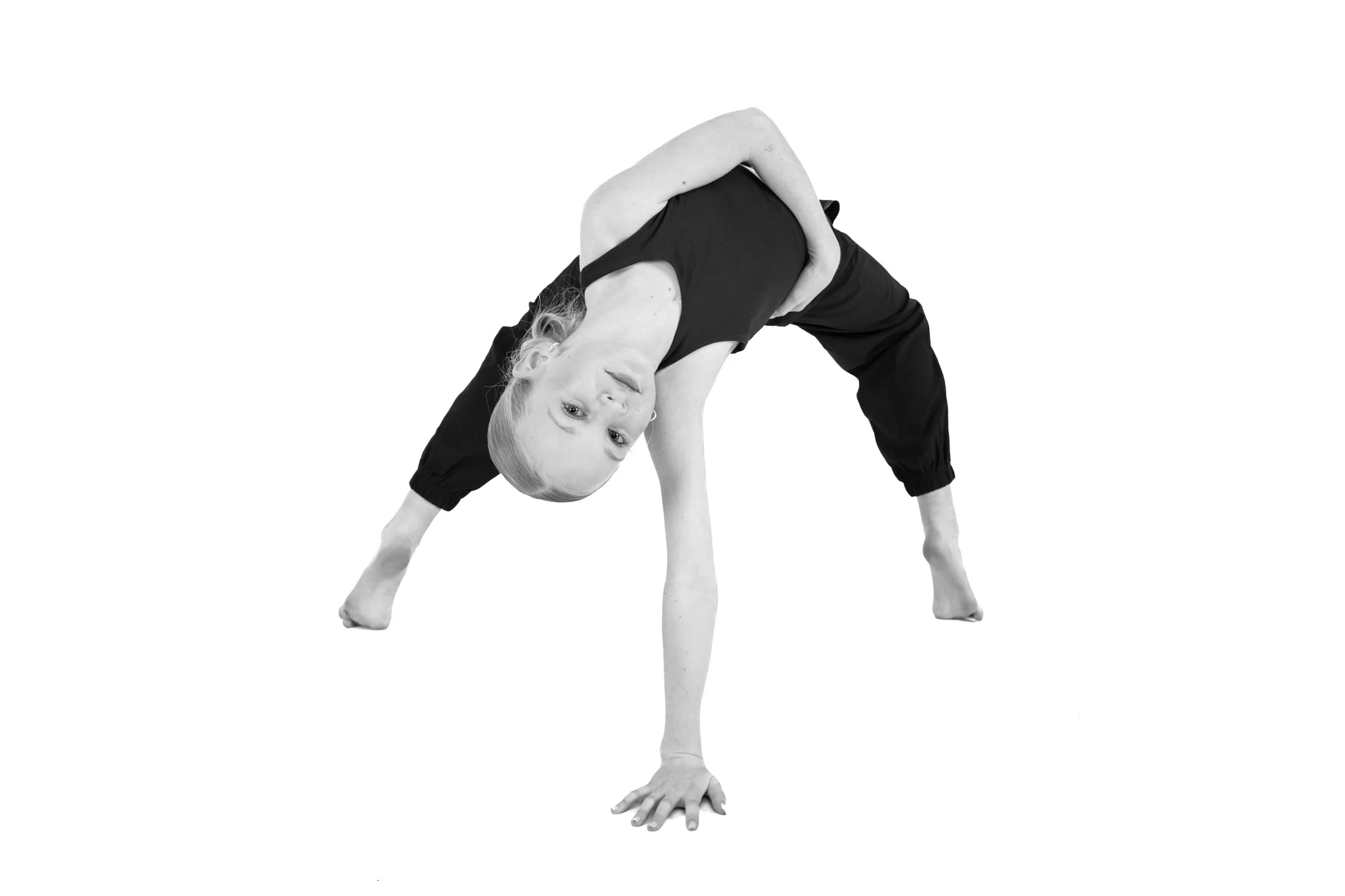A woman doing a yoga pose, leaning on one hand with her legs apart, in black and white.