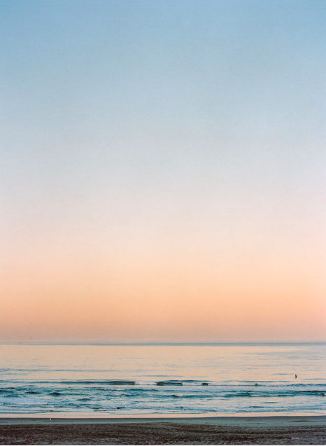 Sunset over the ocean with calm waves and a sandy beach evoking calm somatic healing practice.