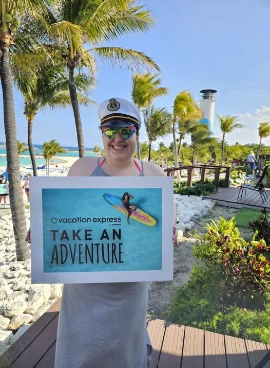 Woman in a captain's hat and sunglasses holding a sign that says 'Vacation Express Take an Adventure' with a beach and palm trees in the background.