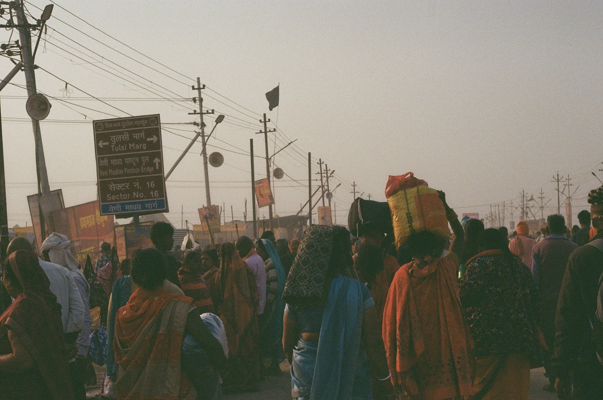 Crowd of people walking on a busy street with power lines and signboards in the background