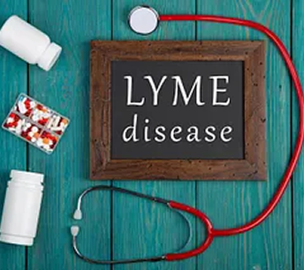 Medical items including a stethoscope, pill bottles, and a blister pack of pills surrounding a chalkboard sign that reads 'Lyme disease' on a teal wooden surface.