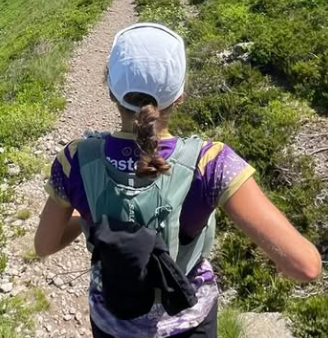 Femme courant sur un sentier de montagne avec un sac à dos, vue de dos.