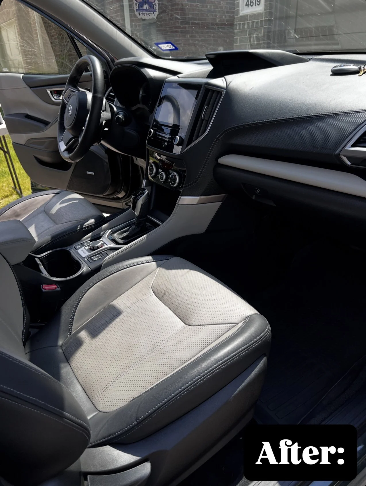 Interior of a modern car showing the driver's seat, steering wheel, dashboard, and center console with a touchscreen and climate controls.