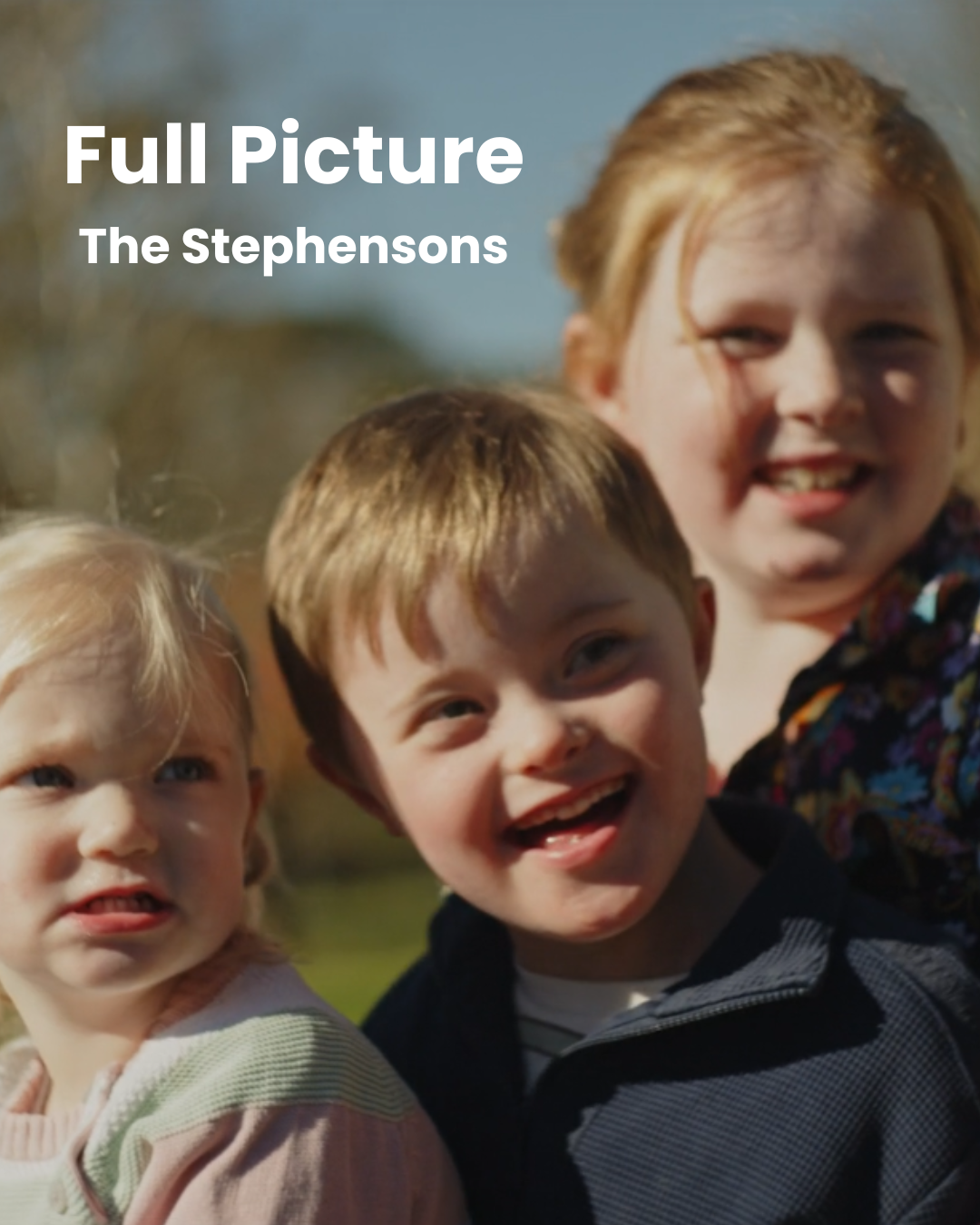 Three children - two girls and a boy - smile at the camera in an outdoor setting. 