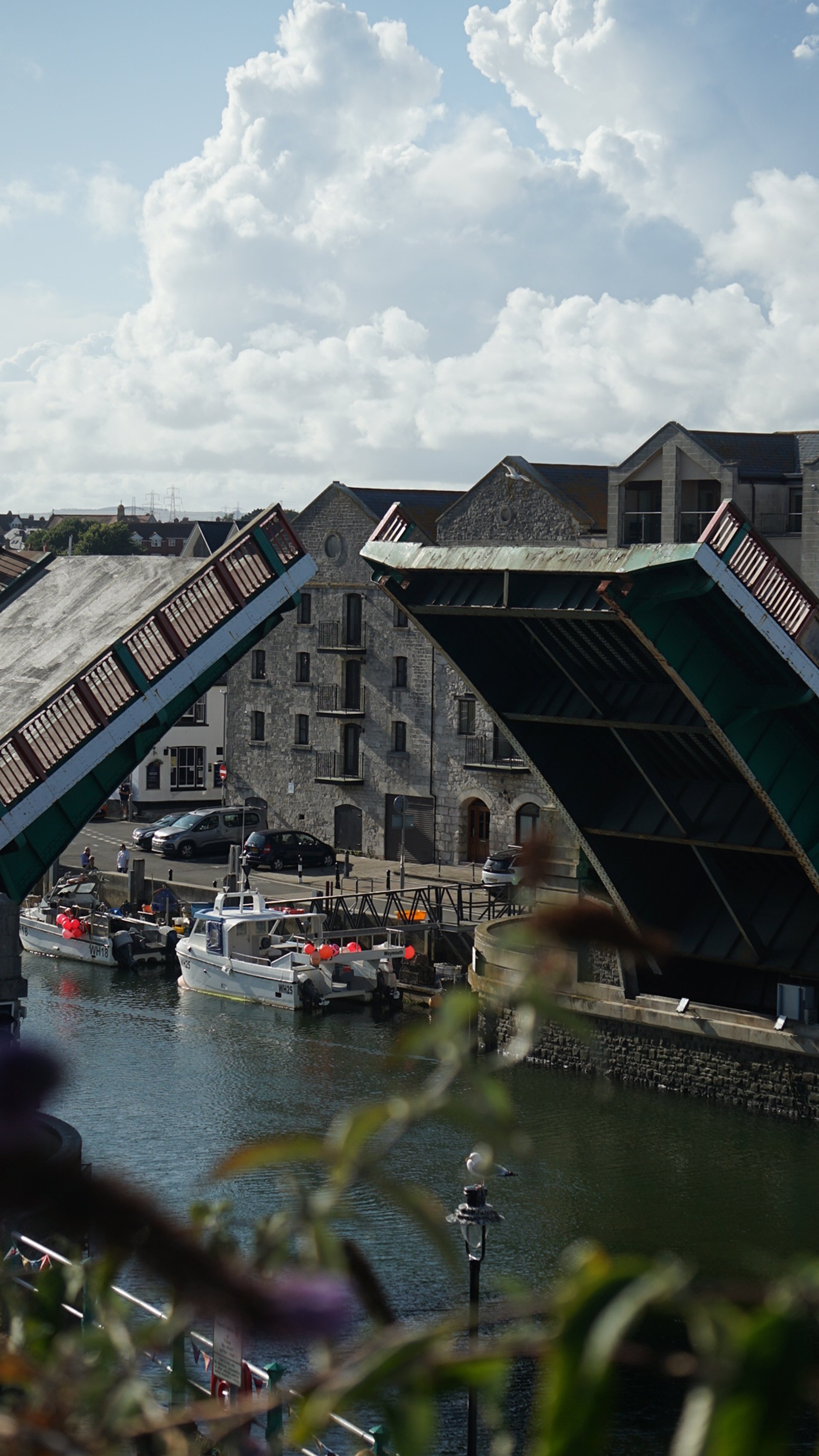 Open drawbridge over waterway with boats and historic buildings in the background