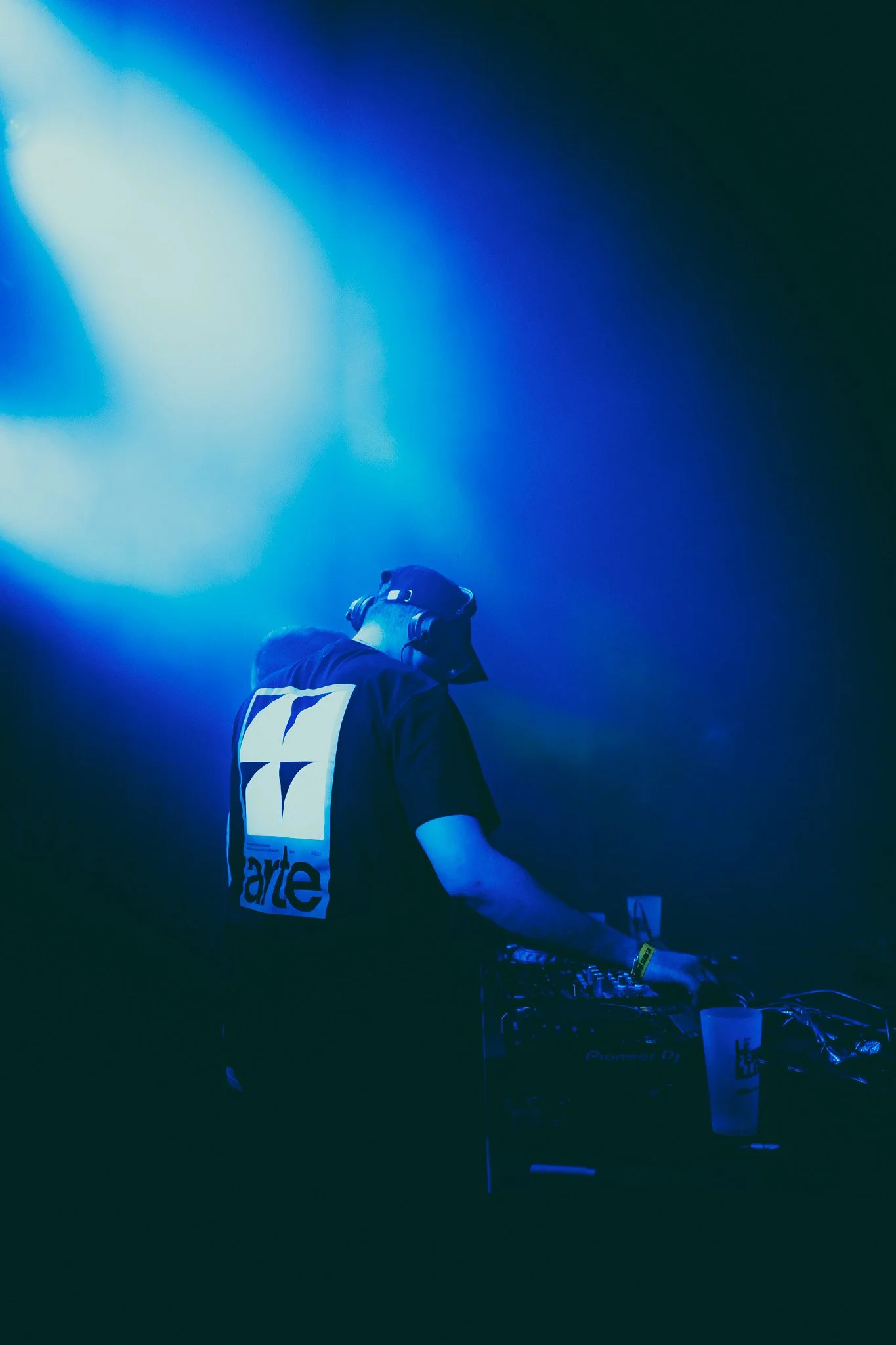 DJ en train de mixer dans un club avec une lumière bleue et verte