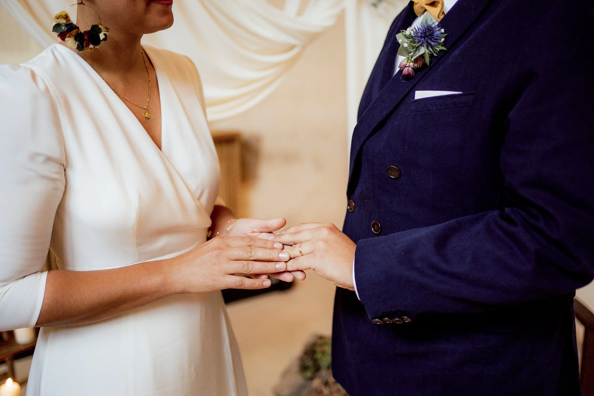 Un couple en robe de mariage échangeant des anneaux lors de la cérémonie.