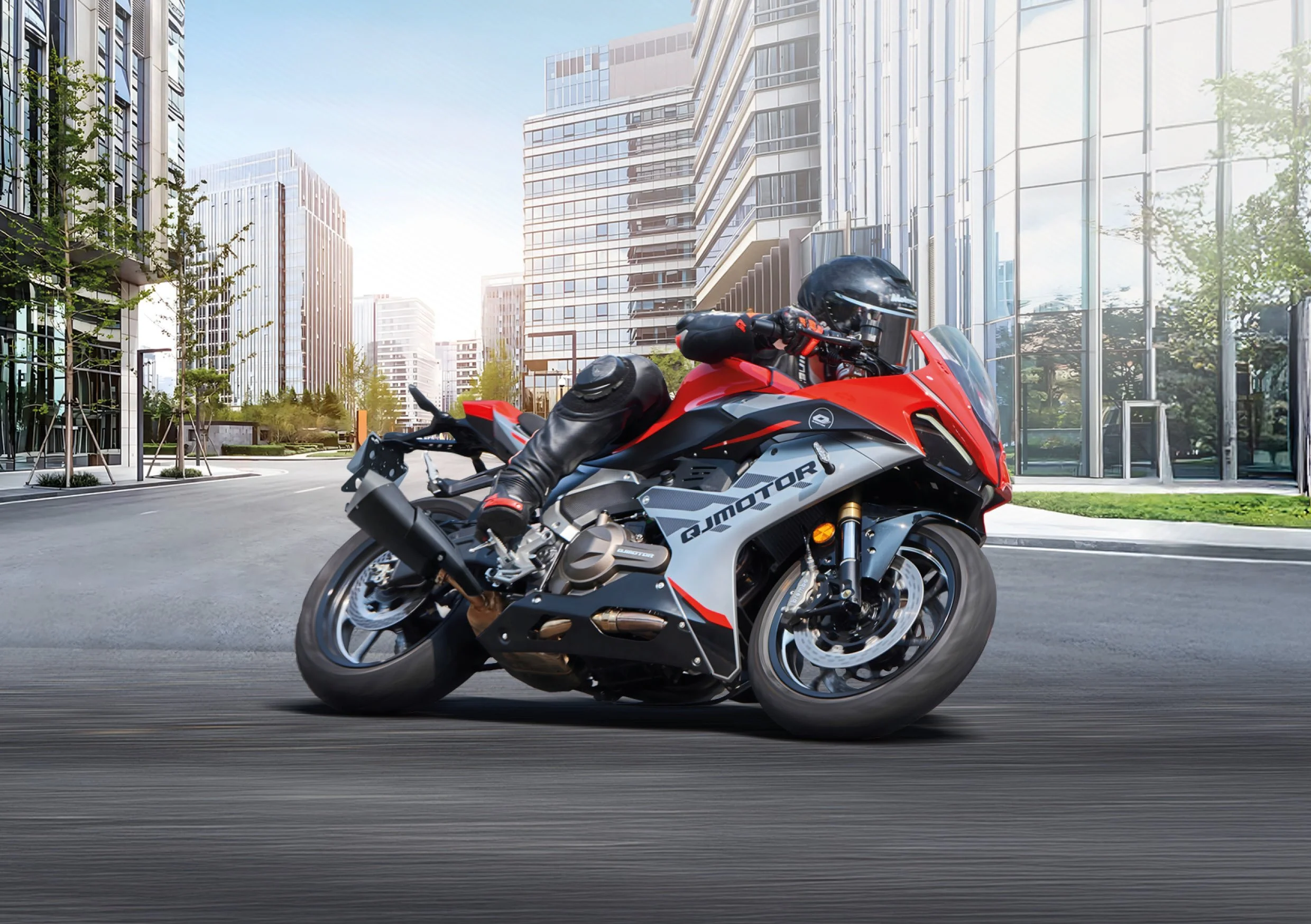 Motard rouge et noir roulant dans une ville moderne avec des gratte-ciel en arrière-plan.