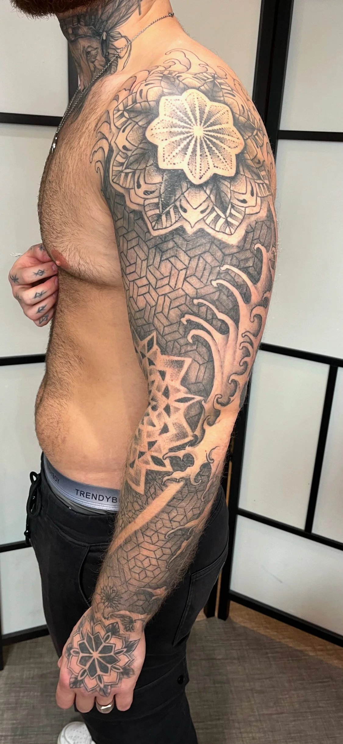 Tatouage géométrique représentant un mandala et des motifs patterns sur l’ensemble du bras.