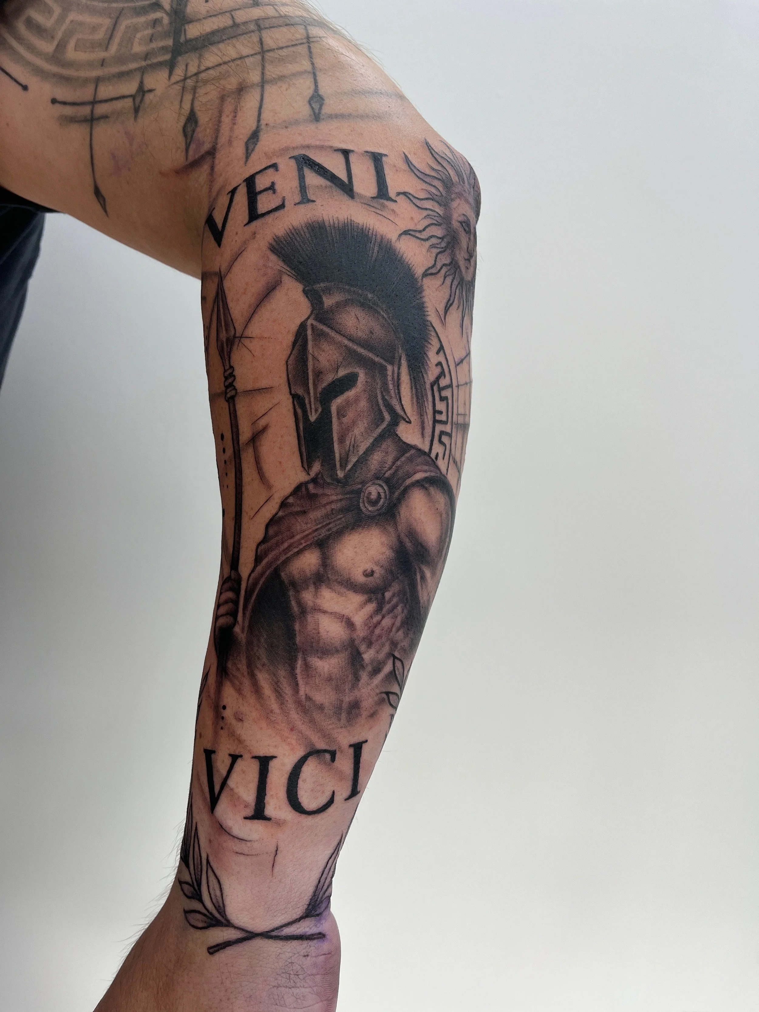Tatouage blackwork représentant un guerrier spartiate avec casque et lance sur le bras.