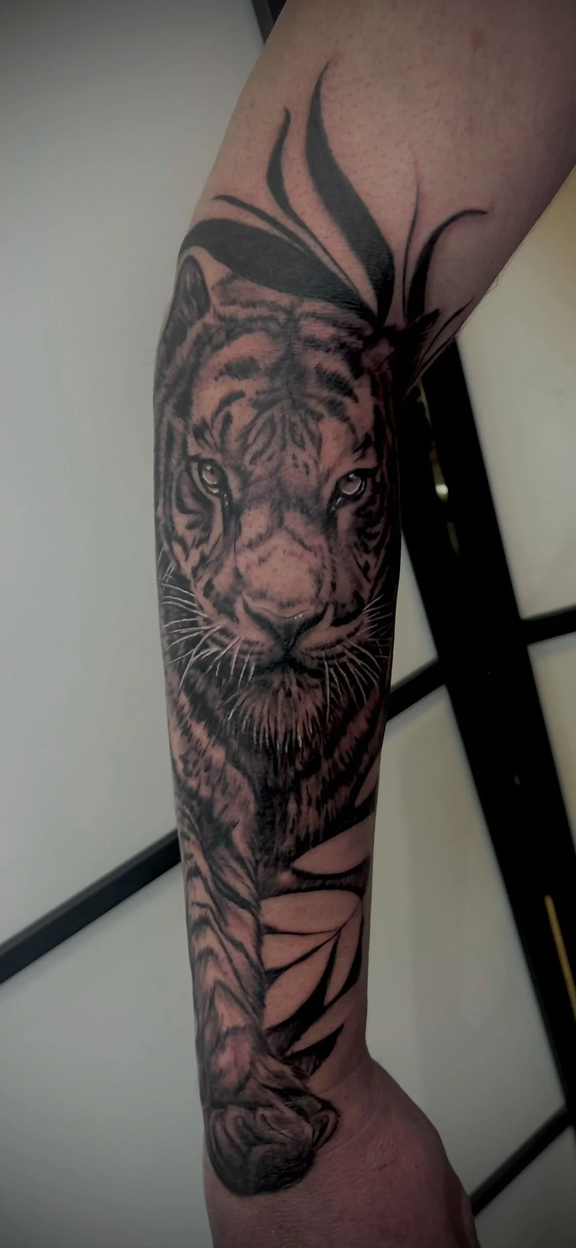 Tatouage réaliste représentant un tigre détaillé en noir et gris sur le bras.