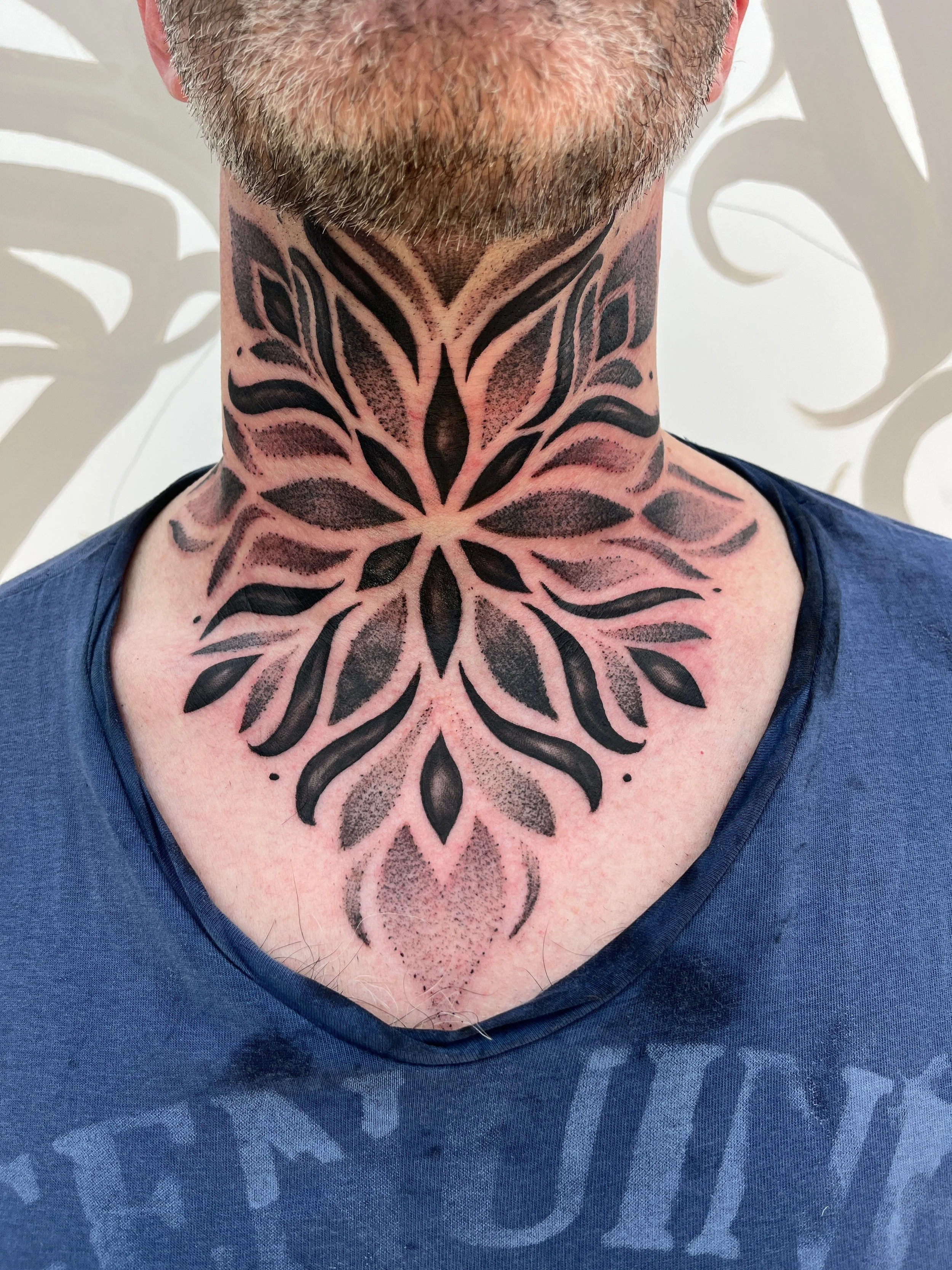 Tatouage mandala géométrique blackwork réalisé sur le cou et le haut du torse.