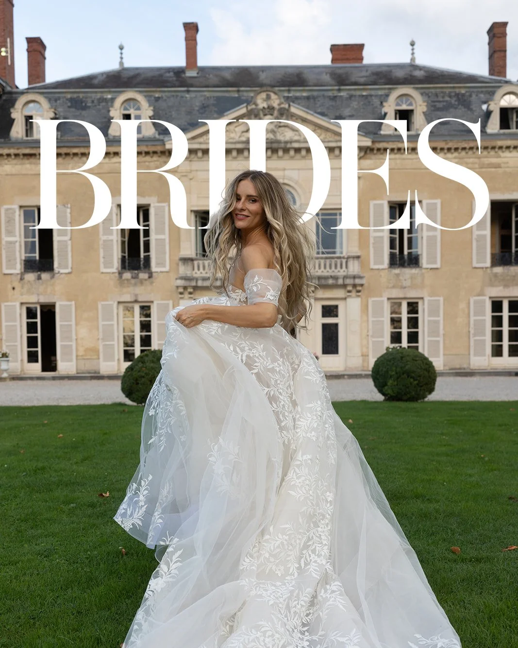 A woman in a wedding dress standing on grass in front of a historic mansion, with large windows and shutters, holding her dress.