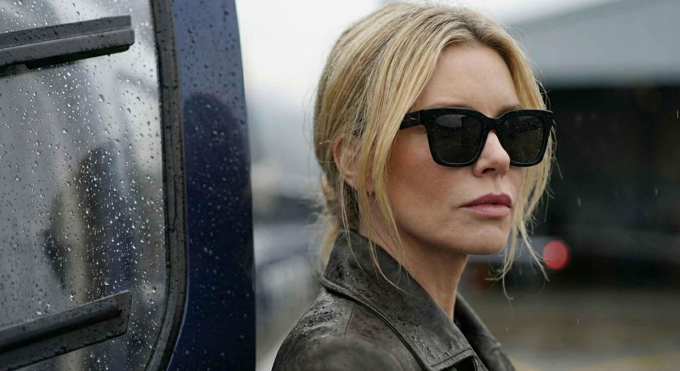 Portrait d’une femme blonde en lunettes de soleil et veste en cuir, ciel couvert