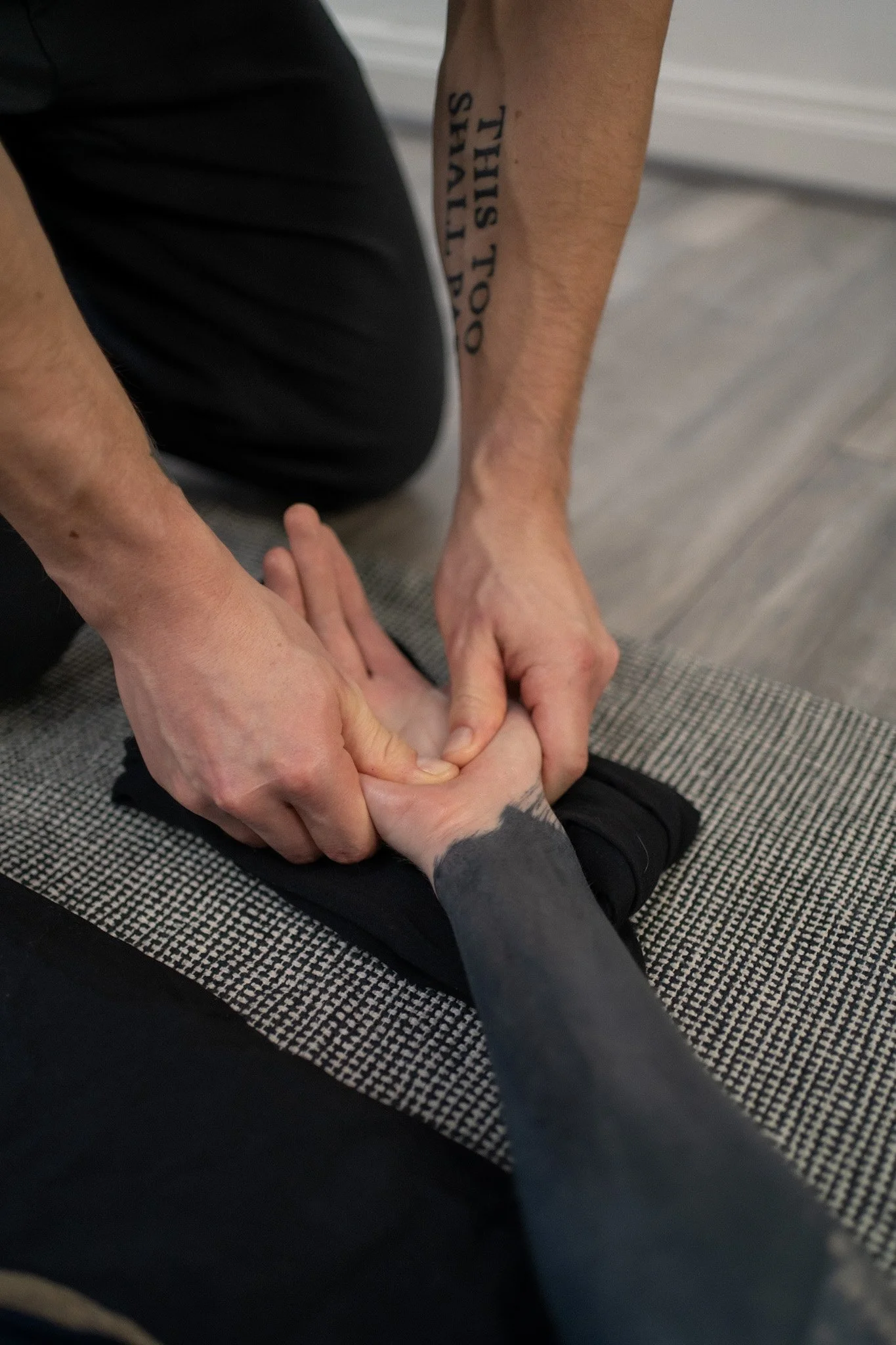 An Ayurvedic Yoga Massage therapist working to release tension in the palm of the client's hand.