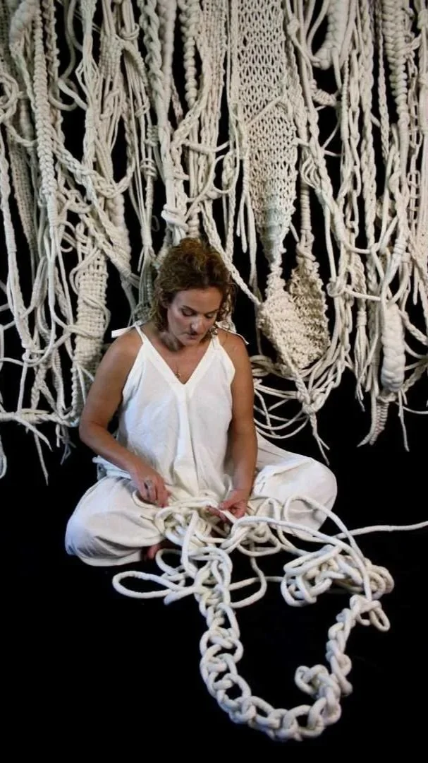 artist sitting on floor working on large scale neutral tone  textile weaving