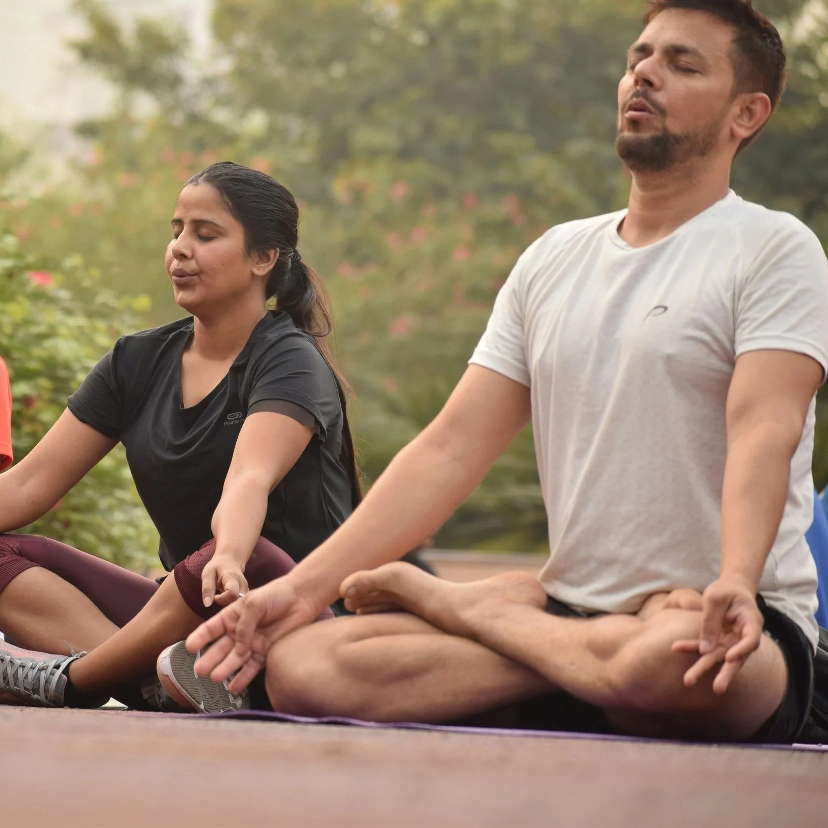 man and woman sitting in nature in meditation pose