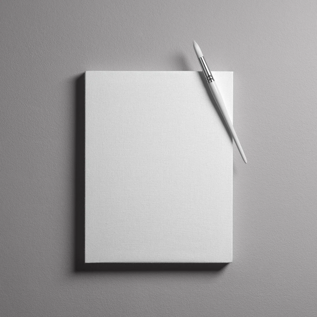 A blank white canvas with a white paintbrush resting on top, placed on a textured light gray surface.